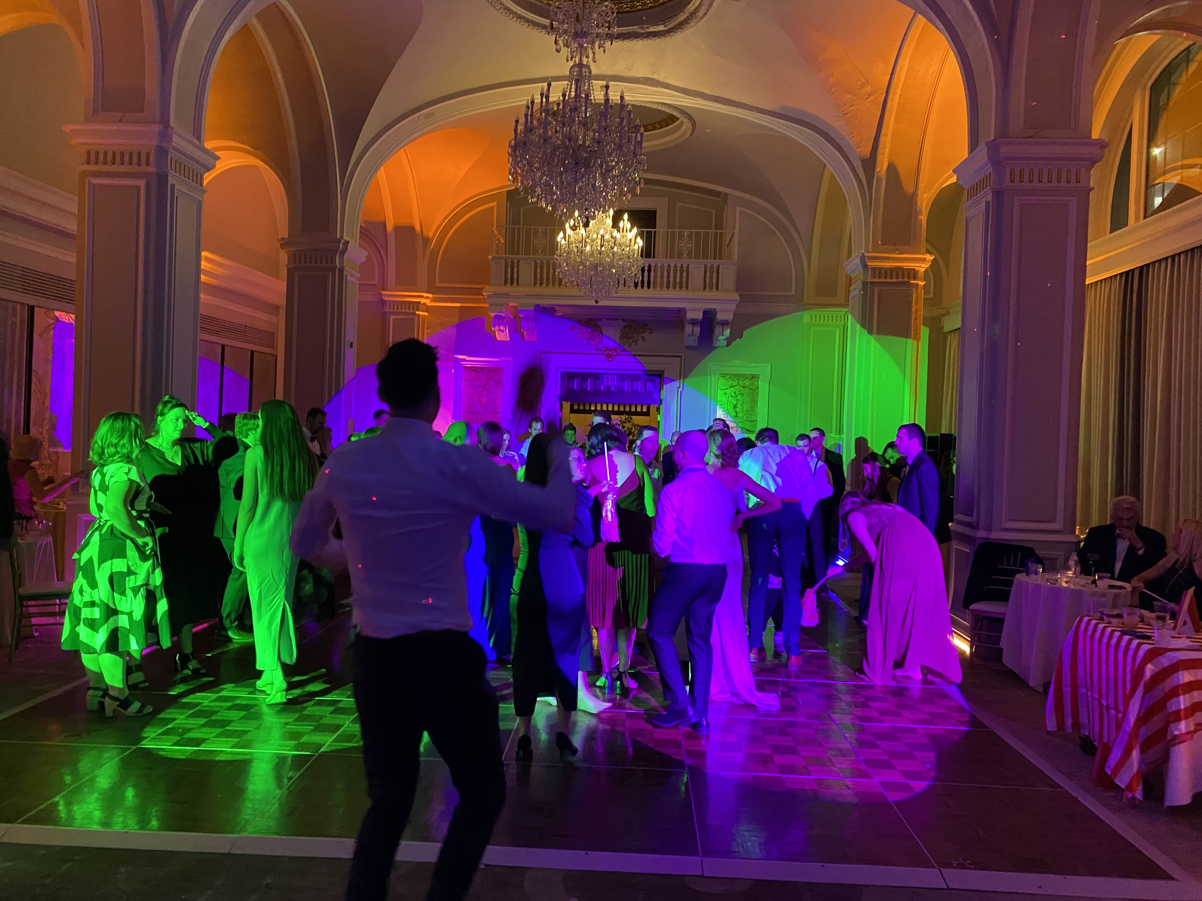 Elegant ballroom with vibrant purple and green uplighting